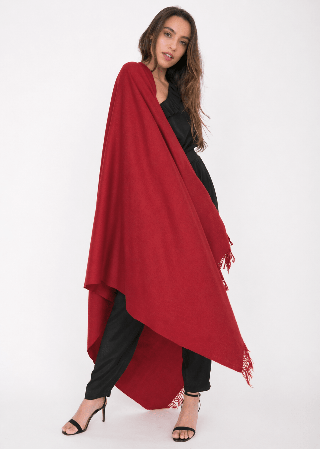 Woman wearing a red blanket scarf and black outfit on a white background