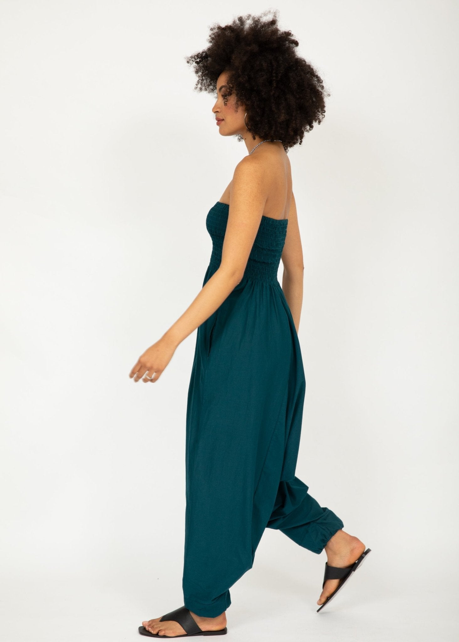 Woman wearing a strapless teal jumpsuit on a white background