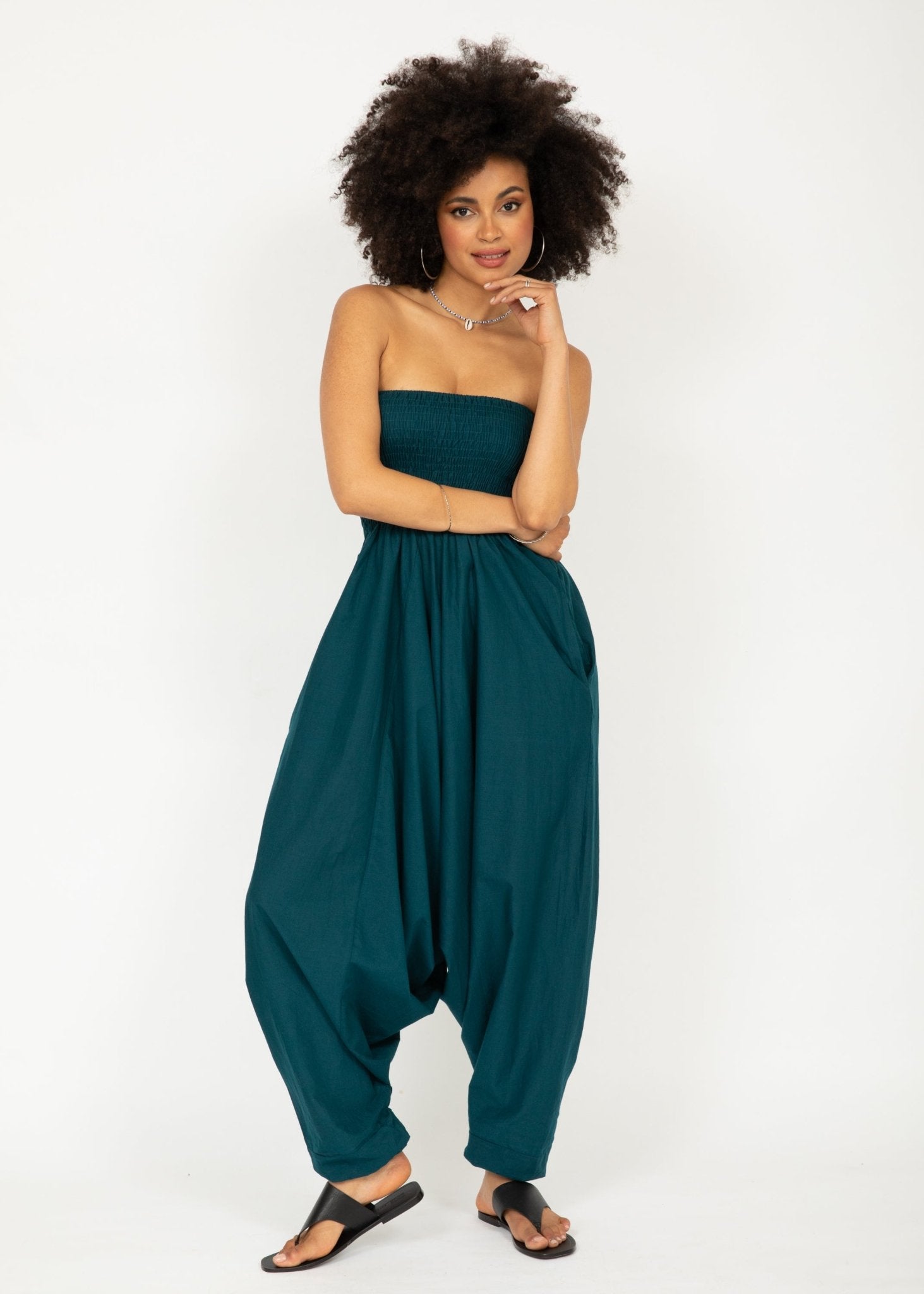 Woman wearing a teal strapless jumpsuit on a white background