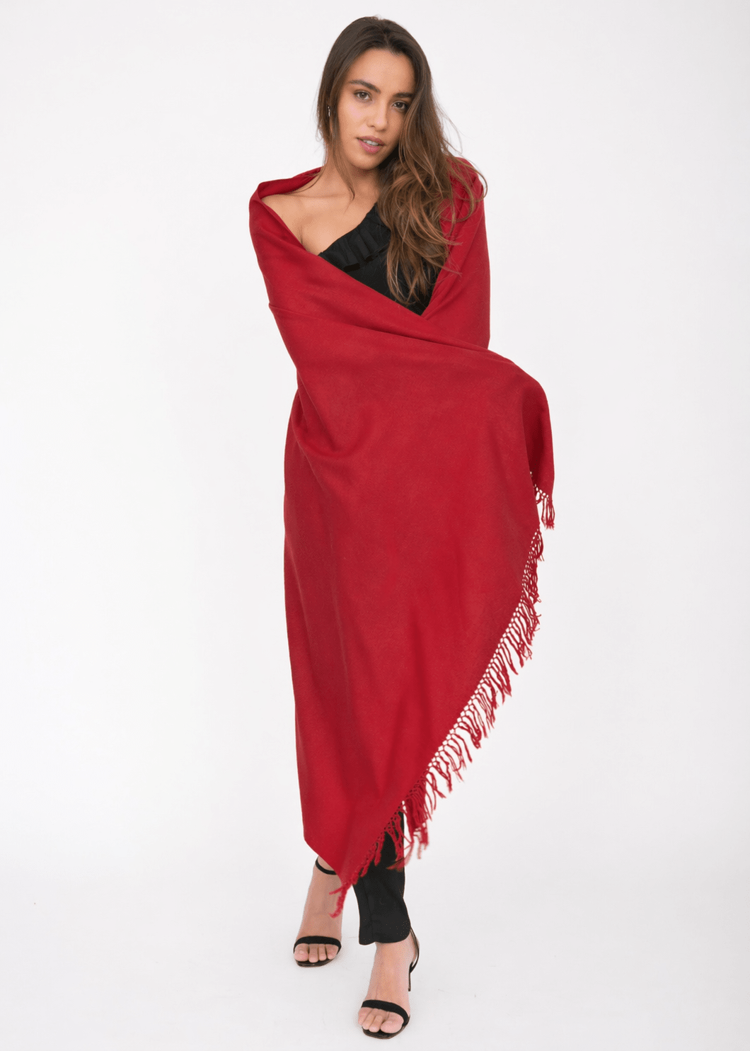 Woman wearing a red blanket scarf with a jumpsuit.