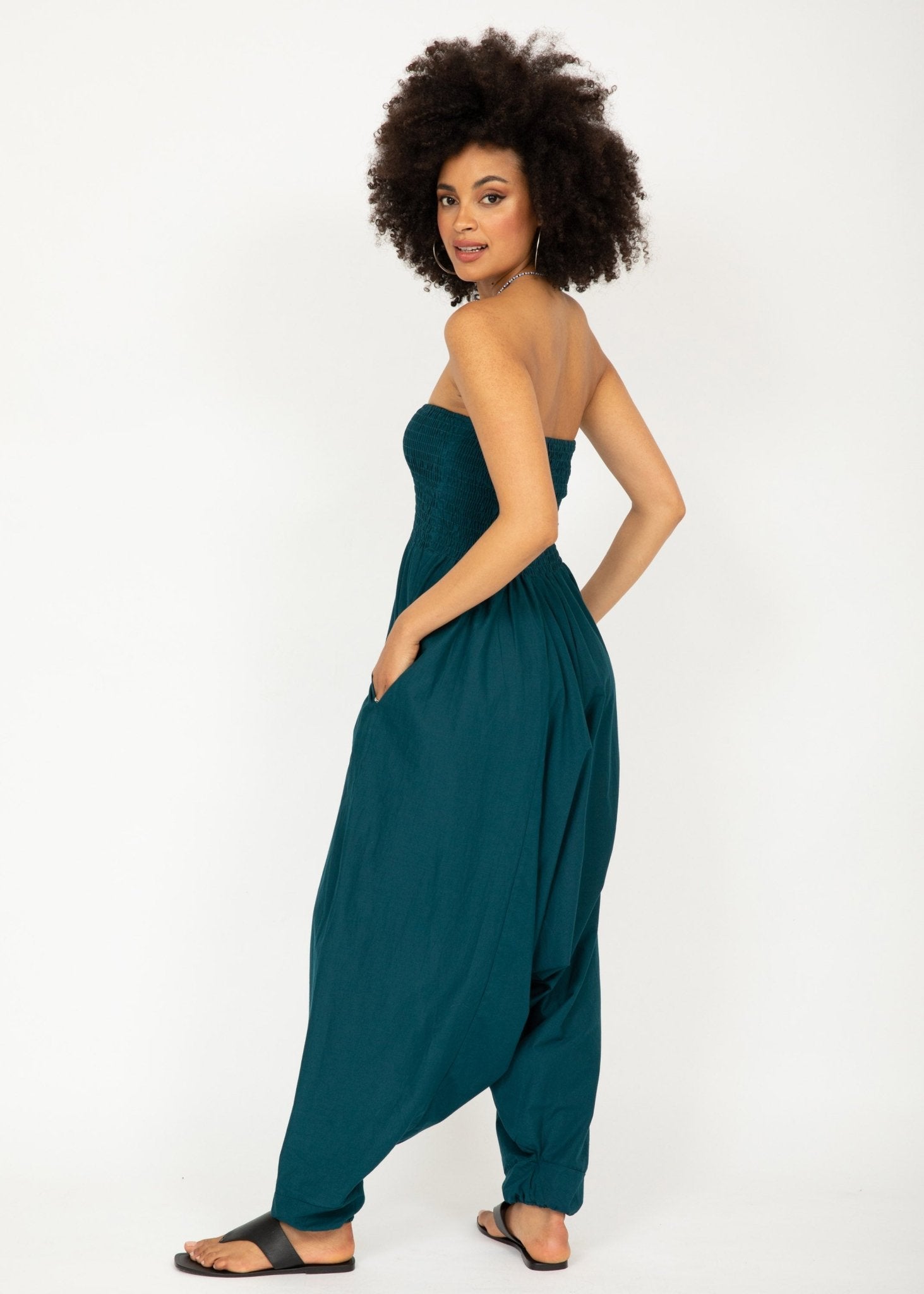 Woman wearing a teal strapless jumpsuit on a white background